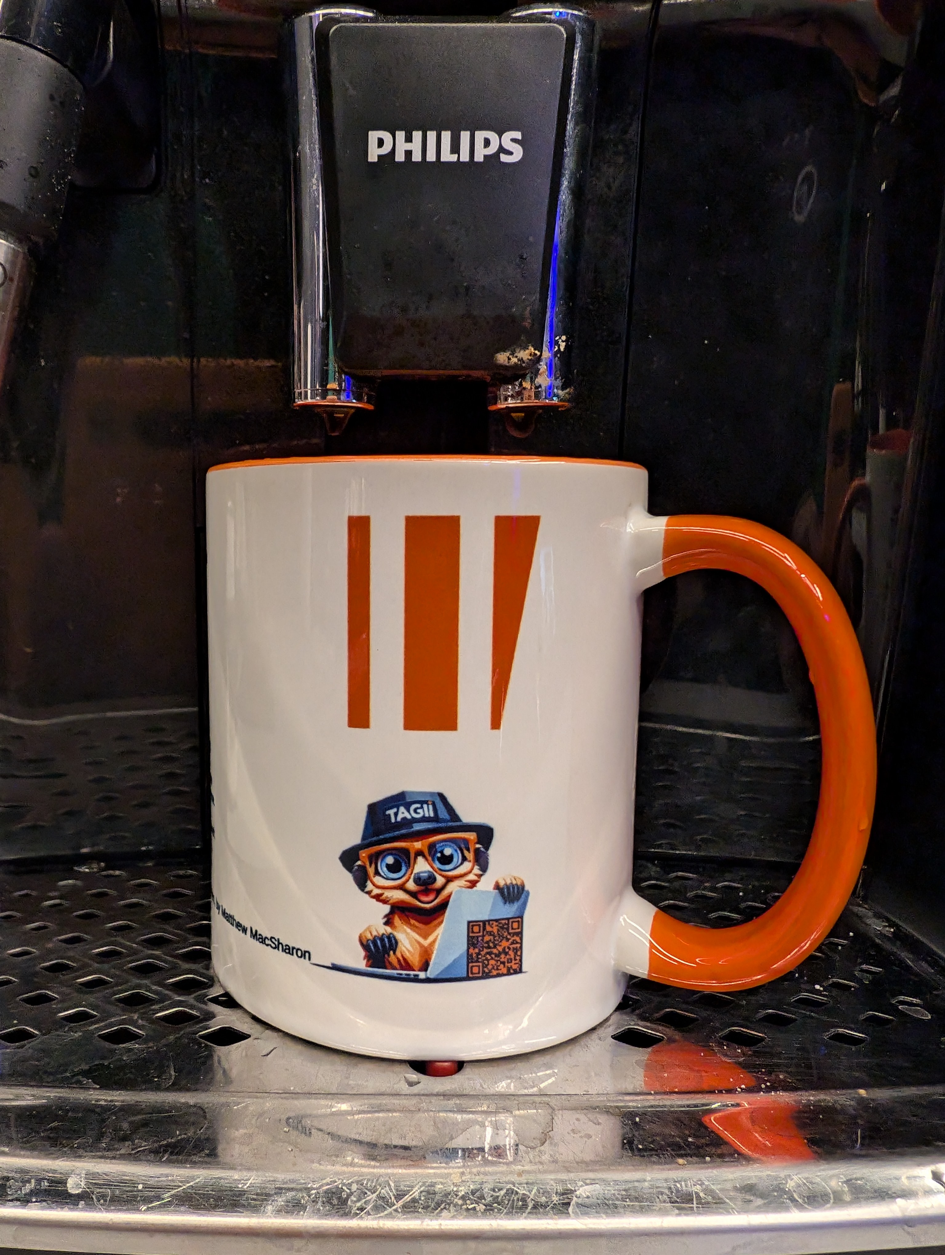 The TAGII mug, with its orange handle and TAGII character, ready for coffee.